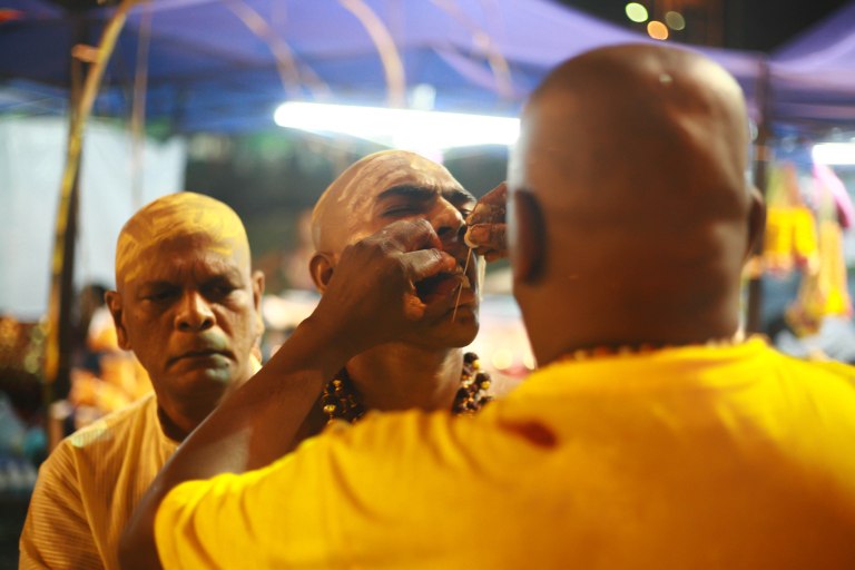 Ramachandran, 55 (L) watch his son, Siva Kumar, 20 (C) as his brother is piercing his son tongue with little javelin as a kavadi outside of the Batu Caves Temple during the Thaipusam festival on February 03, 2015. The Hindu festival of Thaipusam, commemorates the day when Goddess Parvati gave Lord Murugan a Vel, a divine javelin to destroy the evil demon Soorapadman. photo Aizzat Nordin